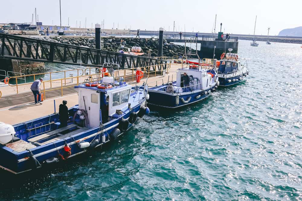 three boats docked at a small harbor with a pier leading down to it 