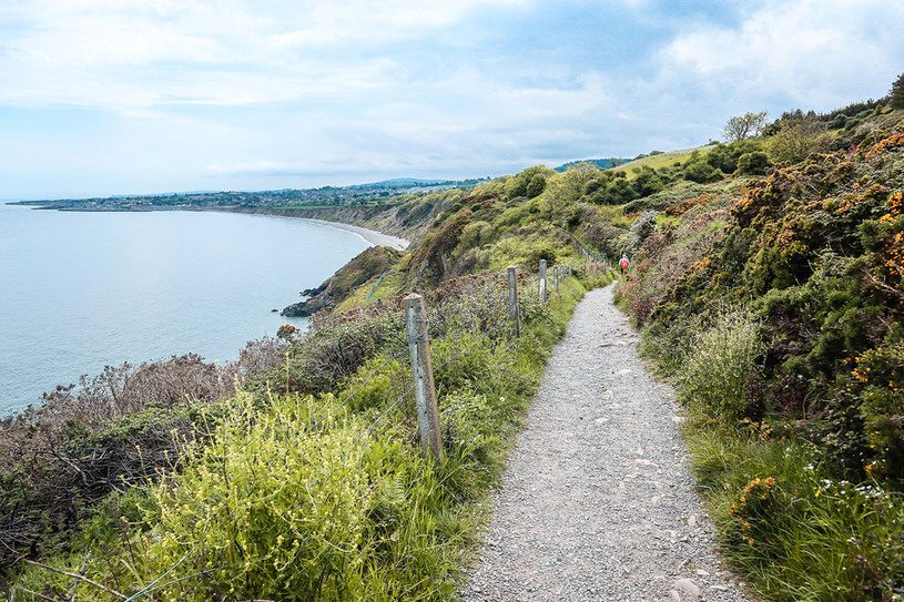 small gravel hiking path along the edge of a cliff overlooking the water