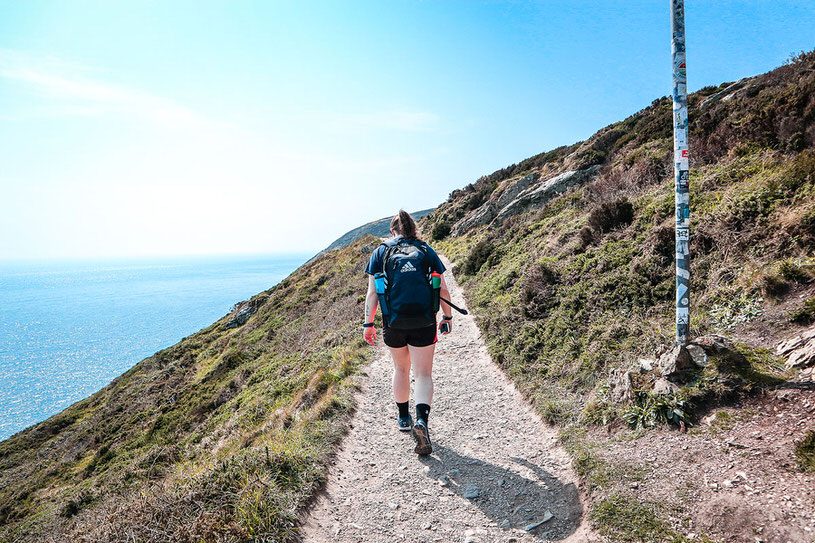 girl walking on the howth cliff walk next to the water.