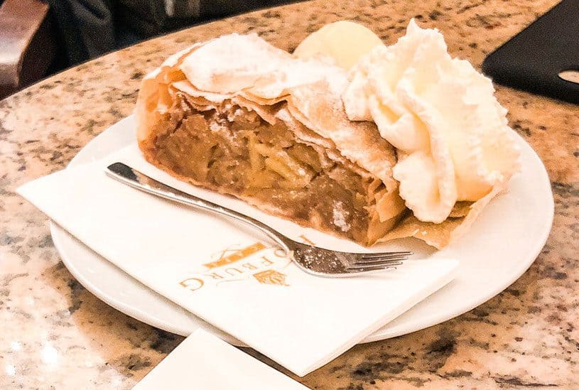 Apple strudel with whip cream on a white plate at Hofburg Cafe in Vienna, Austria.