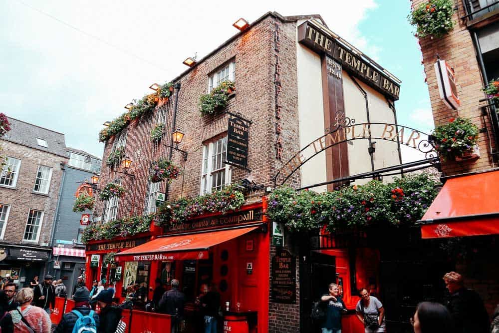 people walking in front of an old stone building that is home to the famous temple bar 
