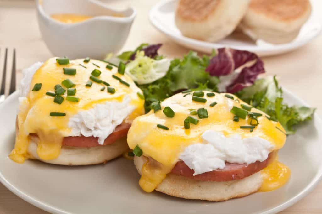 poached egg with sauce and ham on an english muffin