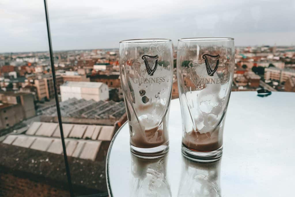 Two empty pint glasses sitting on the edge of a table overlooking a city