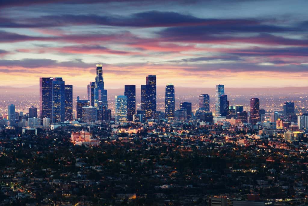 aerial view of a city from far away as it starts to light up as the sun sets