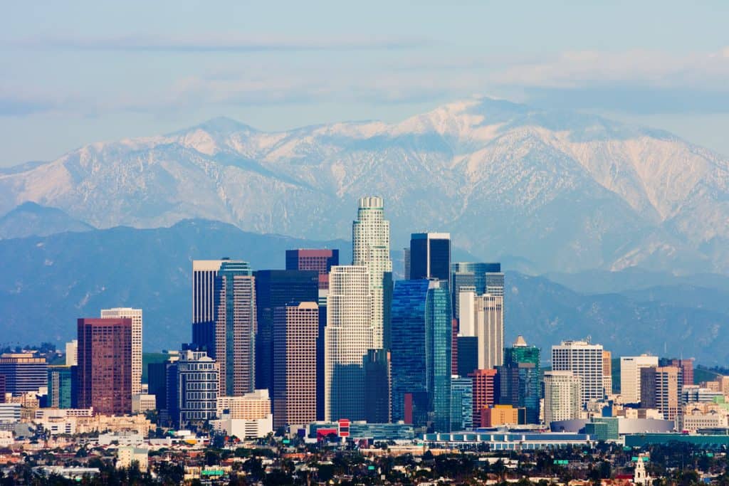 large snowy mountains behind a city skyline with various skyscrapers of different heights