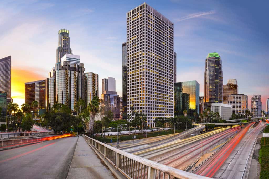 view of a city with skyscrapers from a bridge crossing over a large highway
