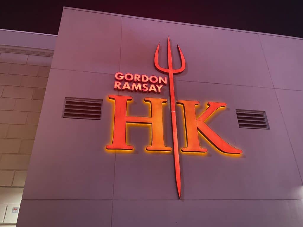 Side of a large white building with a sign on it that says "Gordon Ramsay HK" 
