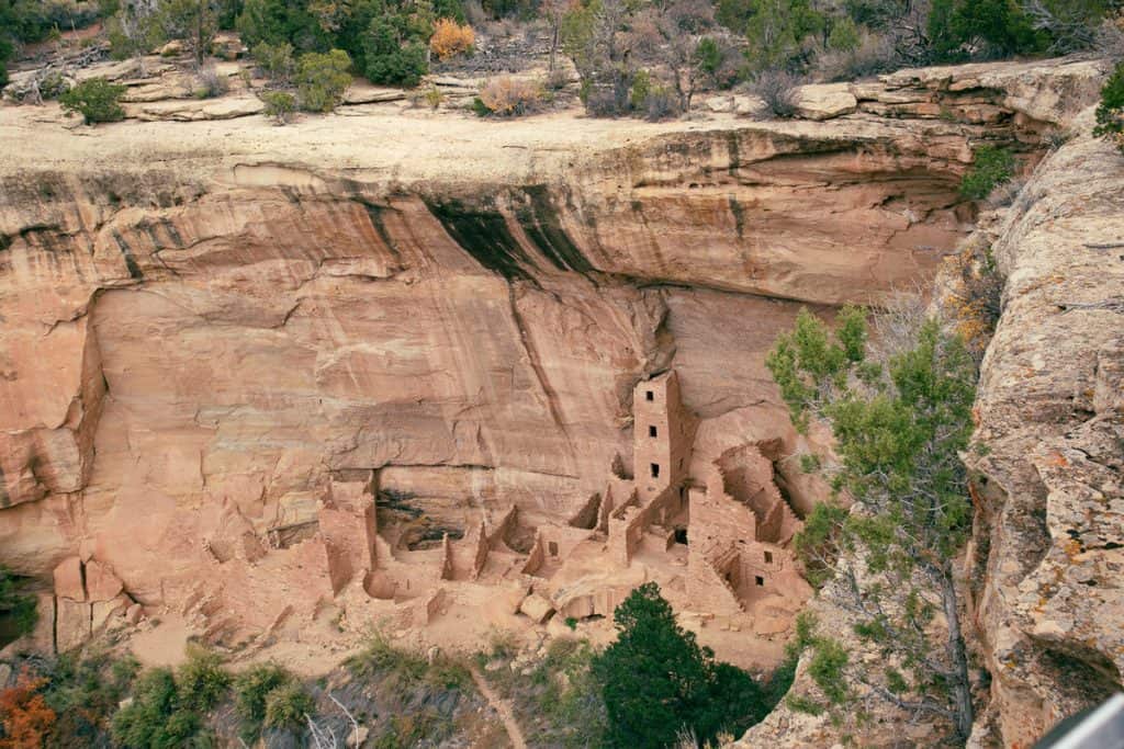 view looking down at the remains of ancient buildings on the side of a rock cliff 