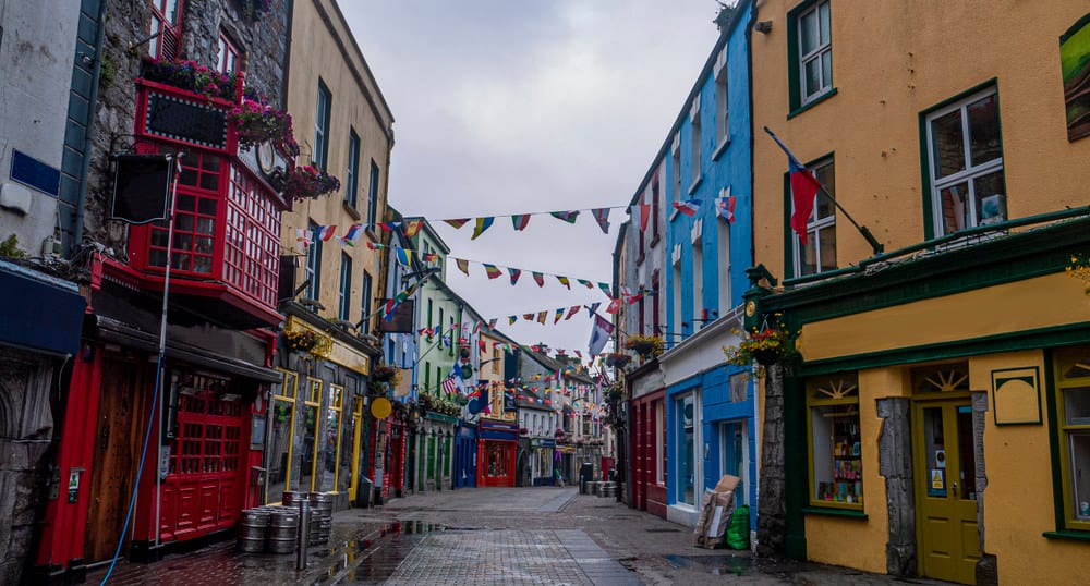 Colorful buildings with small flags hanging between them over a stone walkway 