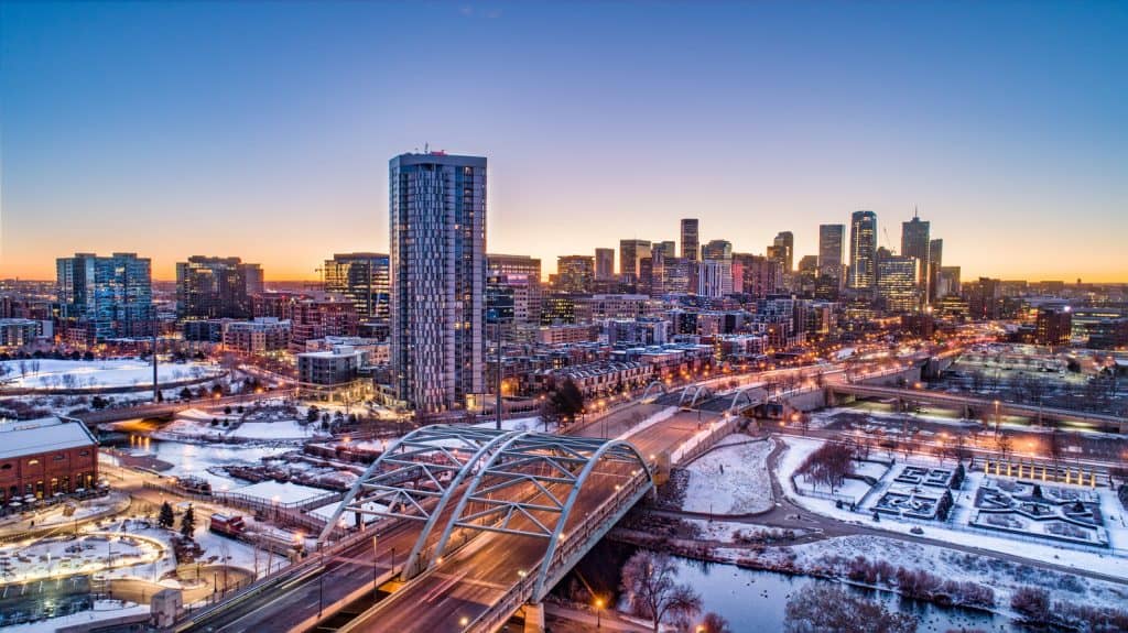 The skyline of a city at night under a blue-yellow sky in winter.
