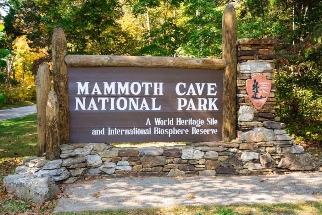 Stone and wood entrance sign to a National Park that says "Mammoth Cave National Park. A world heritage site and international biosphere reserve".