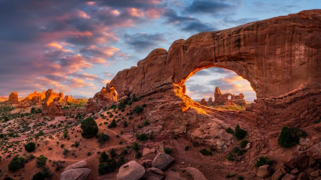 Arch rock formations under a sunset sky.