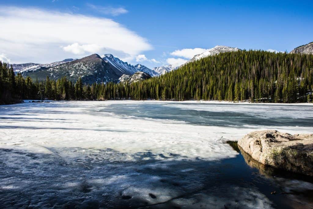 Icy lake next to a forest and mountains