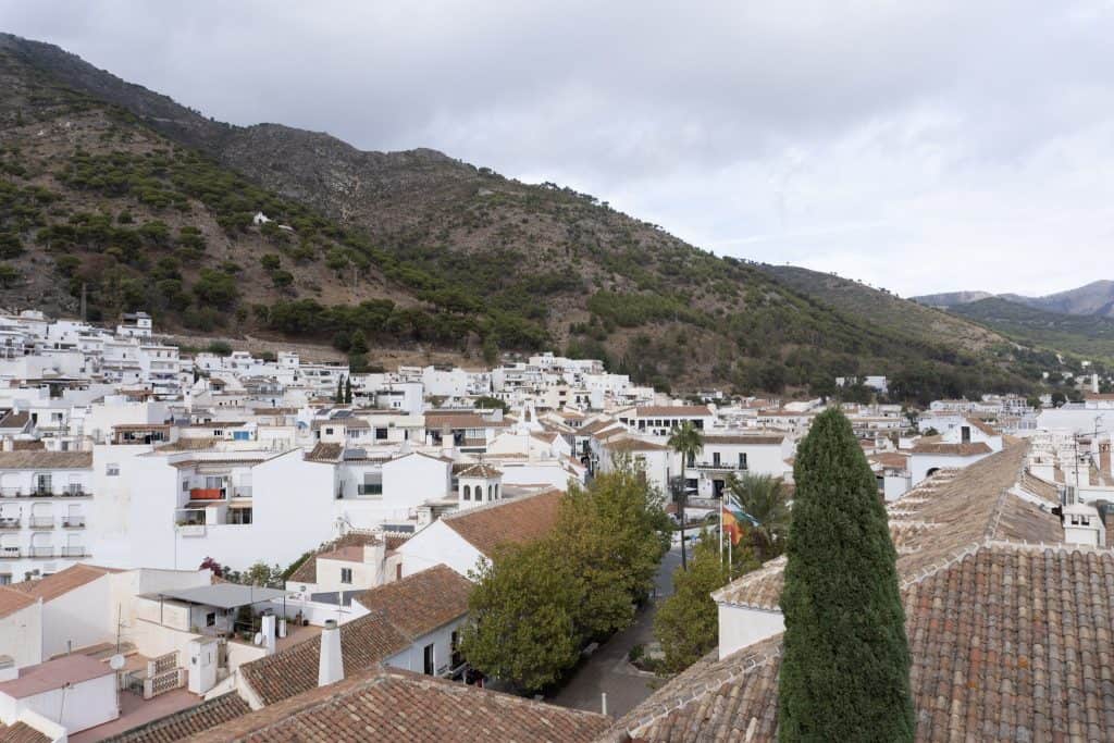 View of white buildings with beautiful rooftops by a mountain.