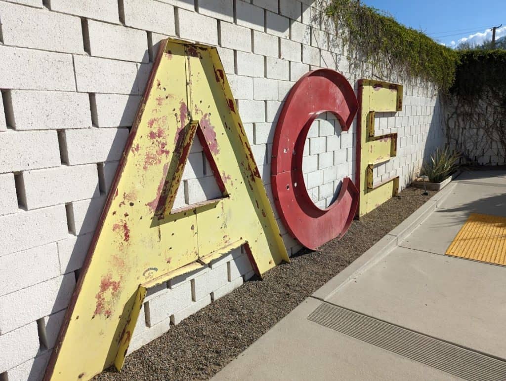 Vintage letters against a brick wall that spell out the word Ace