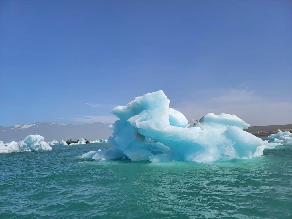 Icebergs floating in Glacier Lagon in Iceland, a large blue lake with the mountains in the distance. 