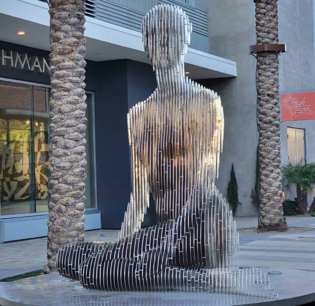 An art sculpture on a city sidewalk of a transparent woman in Palm Springs.