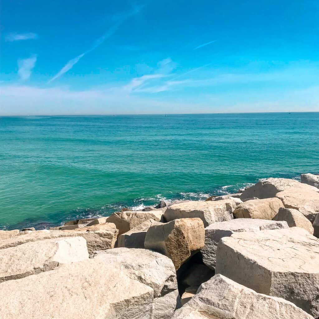 A rocky shorline leading down to a bright blue ocean. 