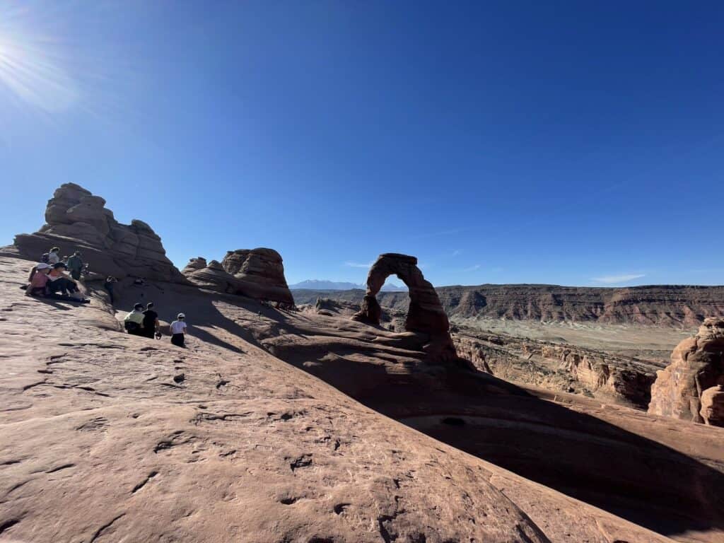 Stone arch in background with hikers overlooking rocky cliffs