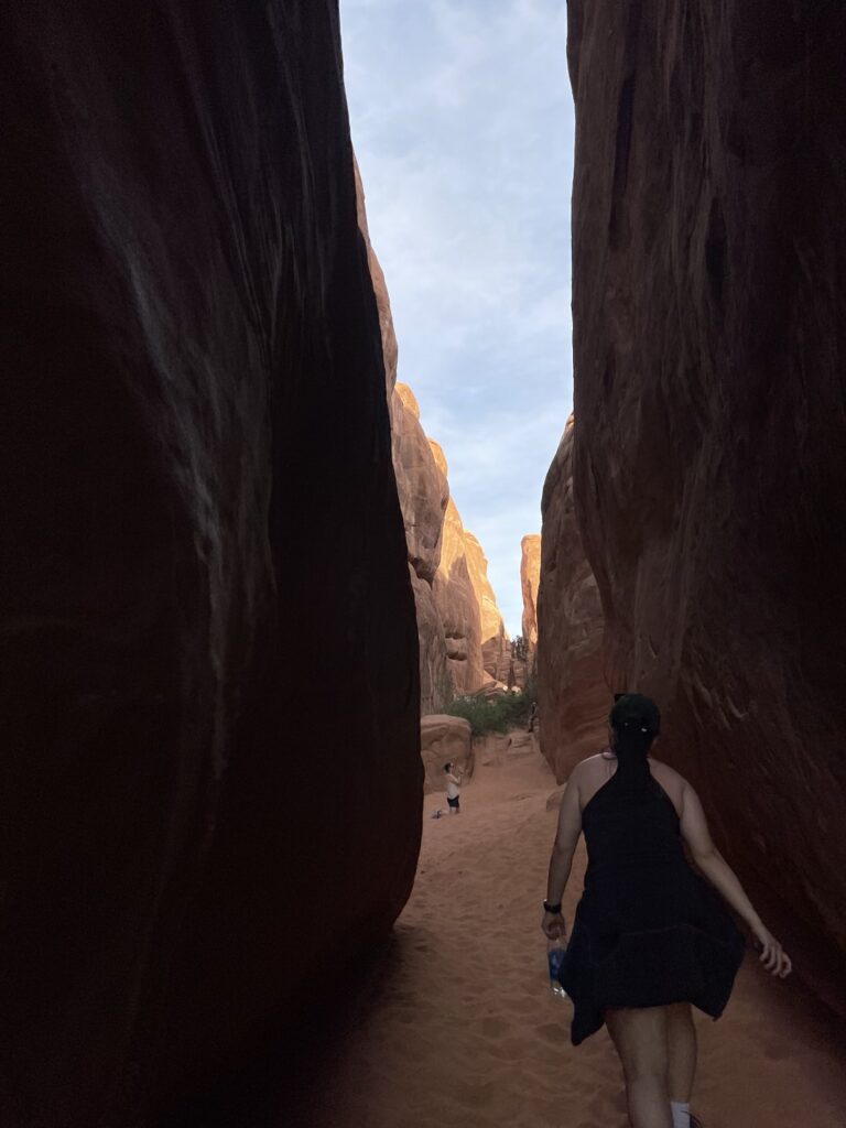 Hiker in black out walking between rocky cliffs