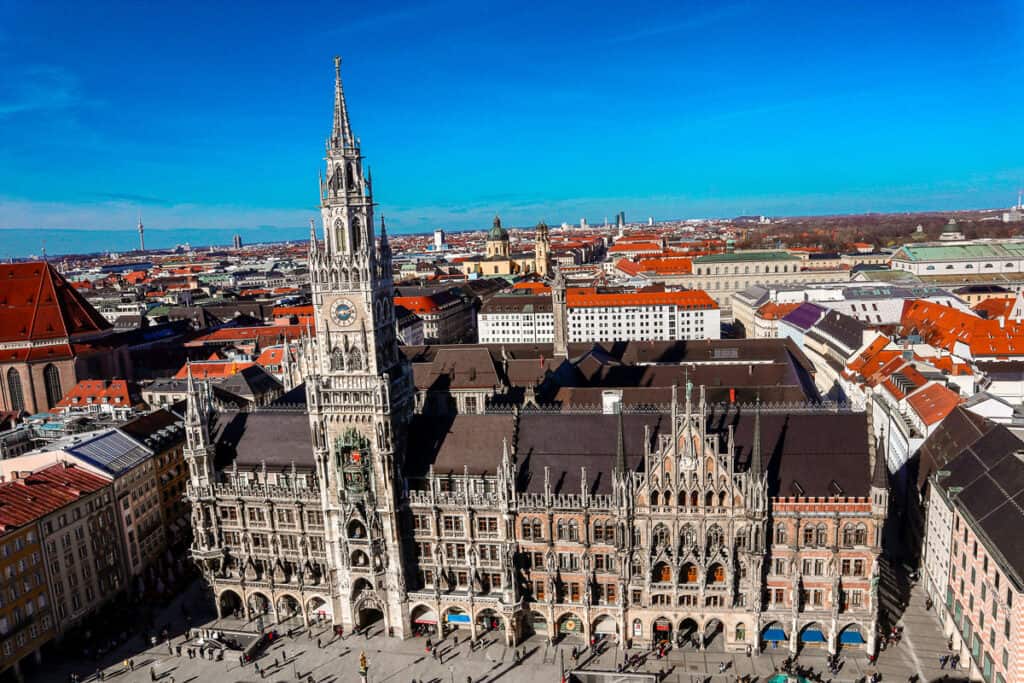 The New Town Hall (Neues Rathaus) in Munich, Germany, with its Gothic Revival architecture, viewed from above, showcasing the intricate facade, clock tower, and the bustling Marienplatz square.