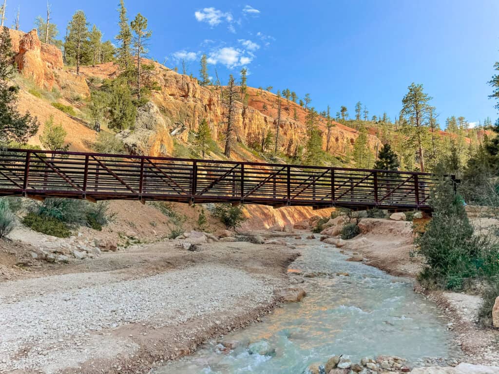 A bridge stretches over a river in Bryce Canyon National Park under a clear, blue sky.
