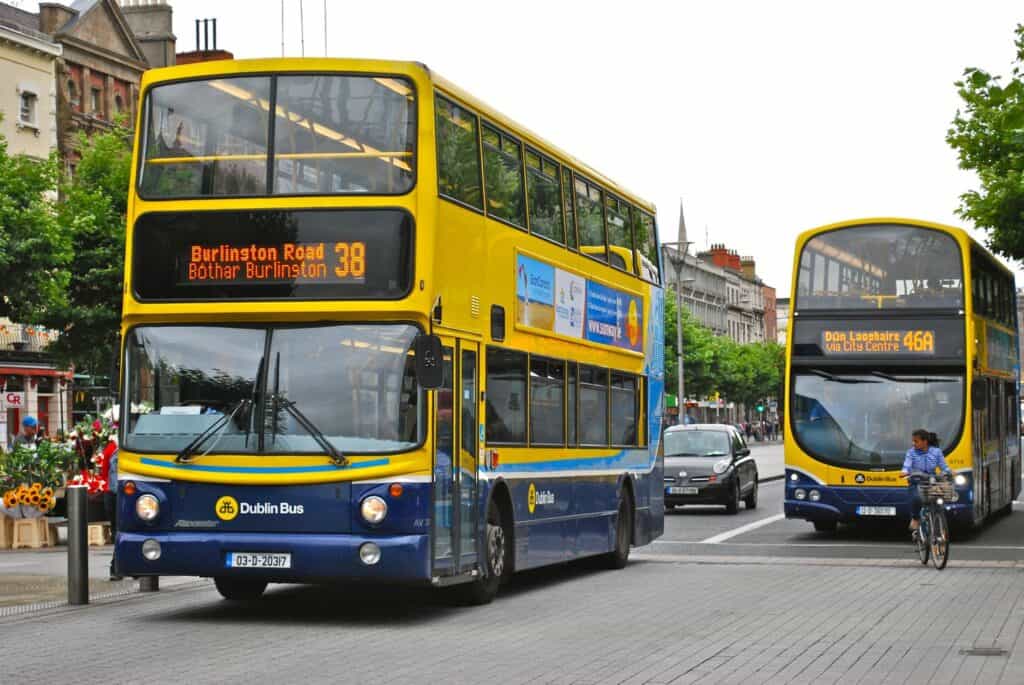 A double-decker Dublin Bus in service, with the route number 38 displayed, sharing the road with cars and a cyclist.