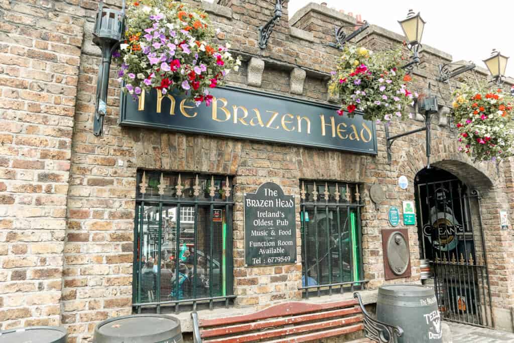 The Brazen Head, proclaimed as Ireland's oldest pub, with its name adorned with vibrant flower baskets, offering live music and food.